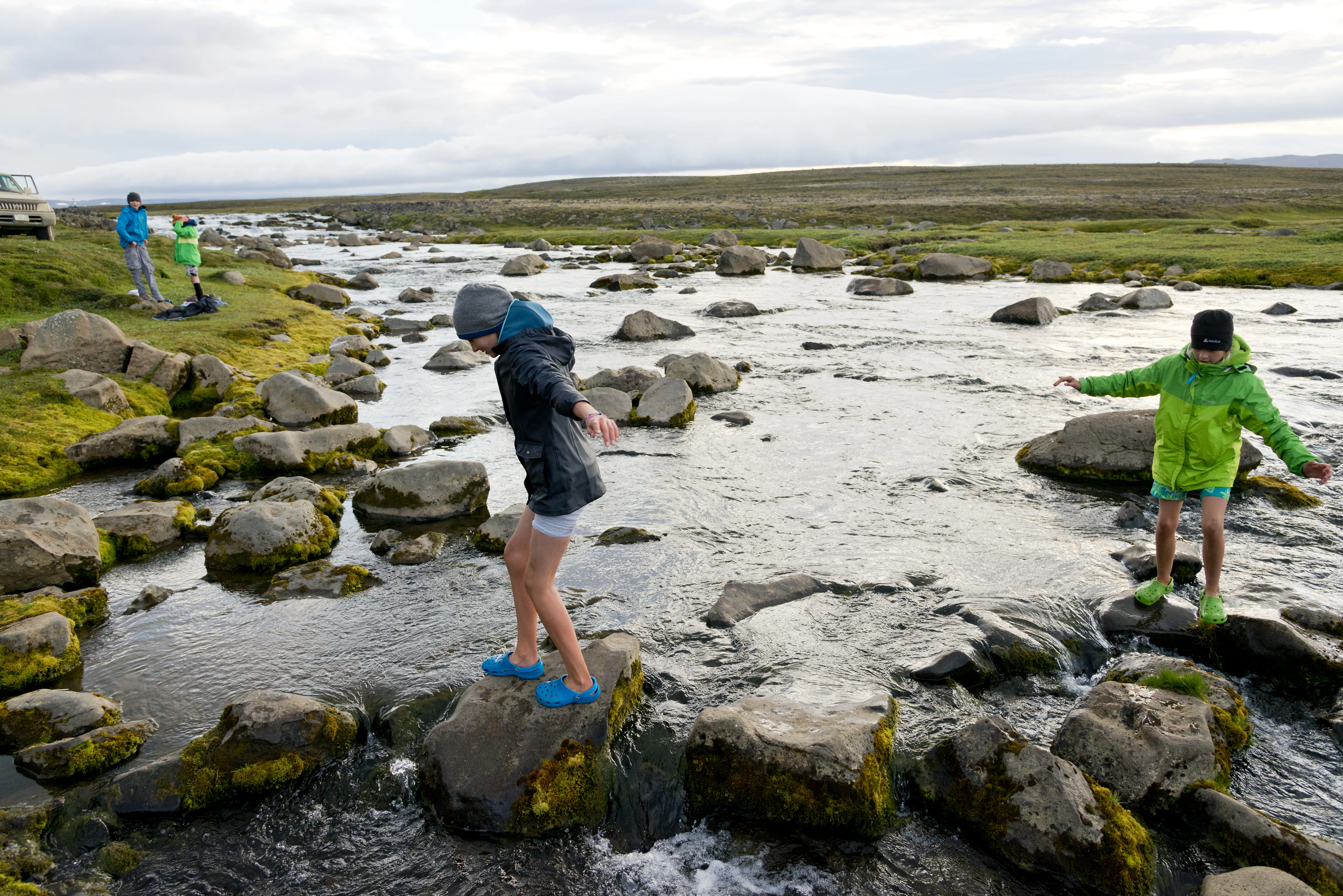 Bach in Islands Hochland, Kinder springen über Steine