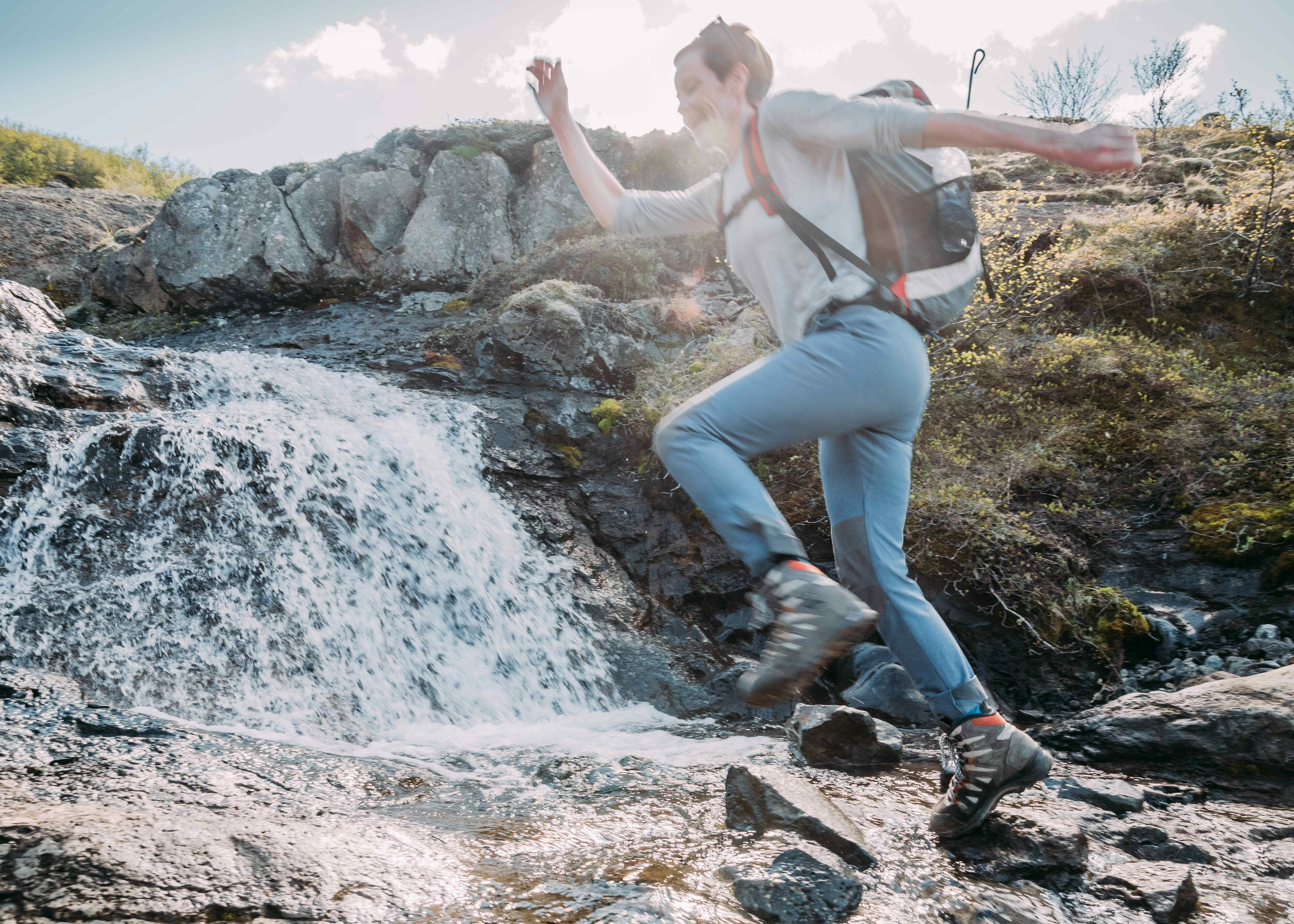 Mitarbeiterin von Katla Travel springt über einen Bach in Island