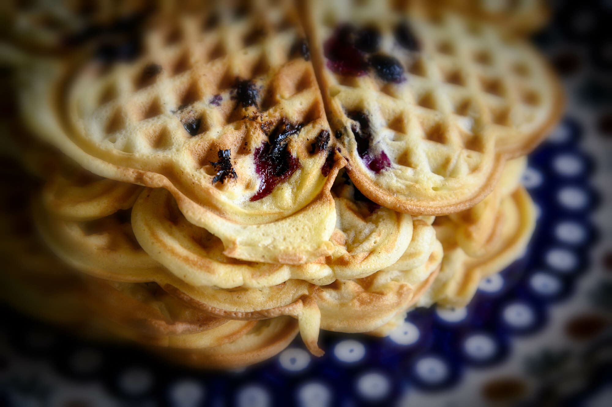 Waffeln mit Blaubeermarmelade in Herzform gestapelt auf einem blauen Teller mit weißen Punkten