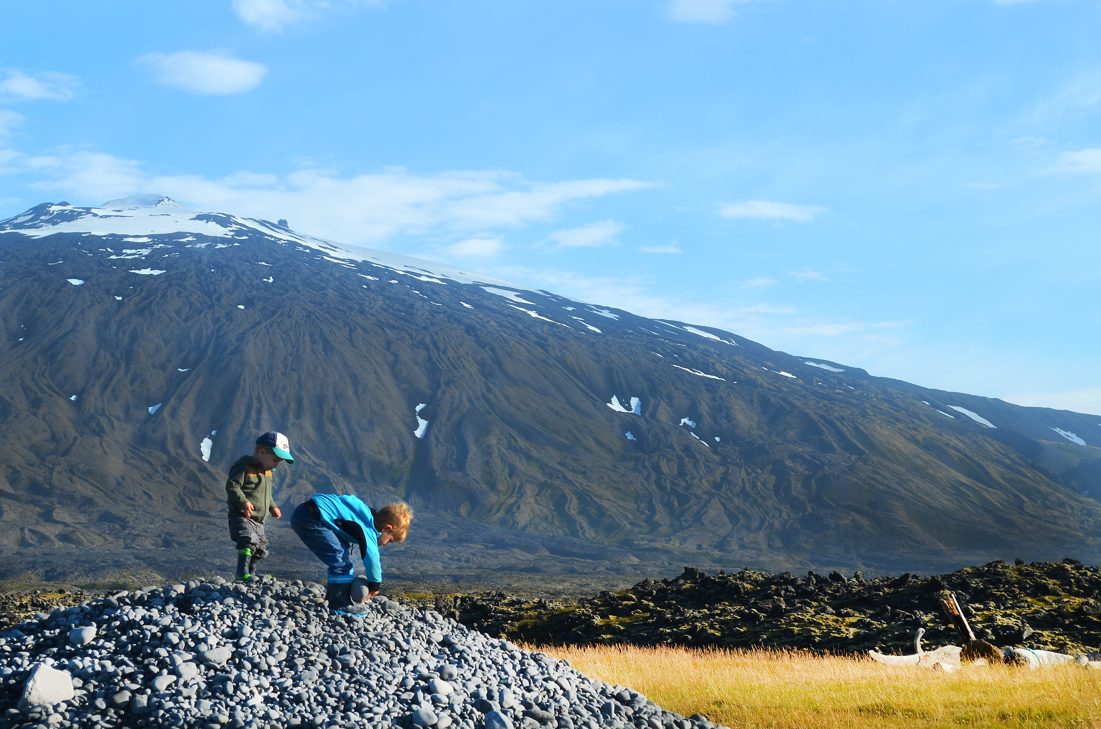 Kinder spielen auf einem Steinhaufen vor den Füßen des Gletscher Snaefellsjökull