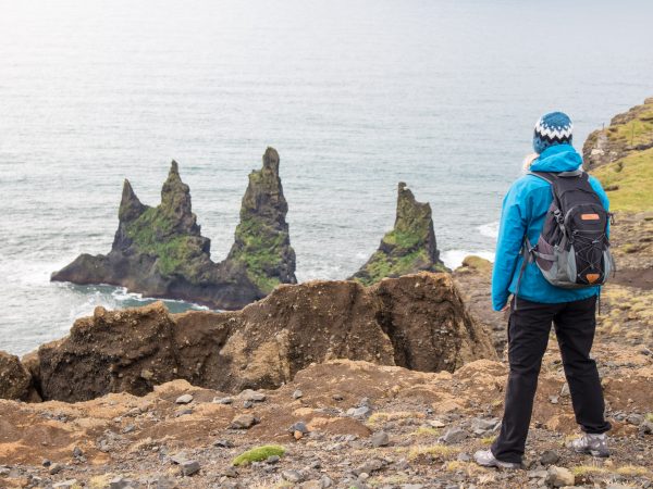 Wanderin genießt die Aussicht auf die Troll-Felsen im Meer in Südisland nahe Vík
