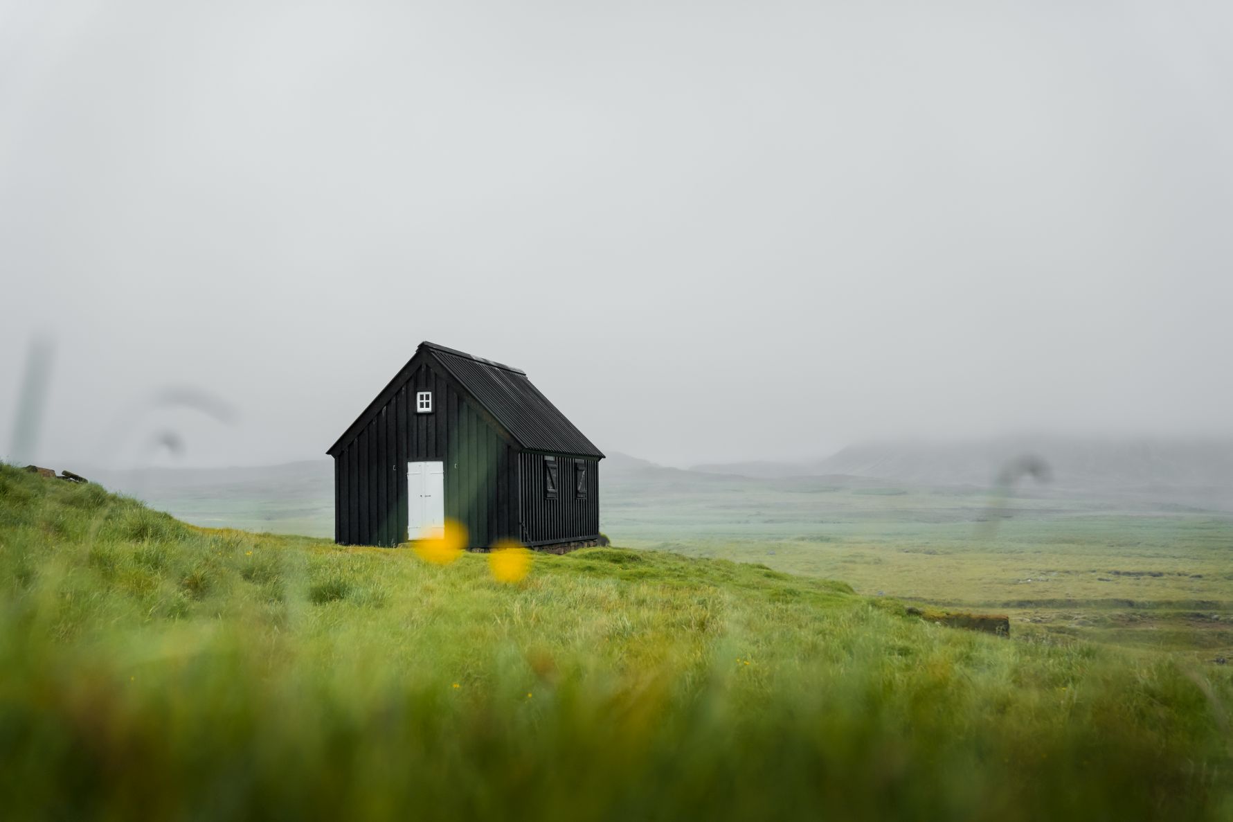 Wiese mit Holzhaus im isländischen Hochland