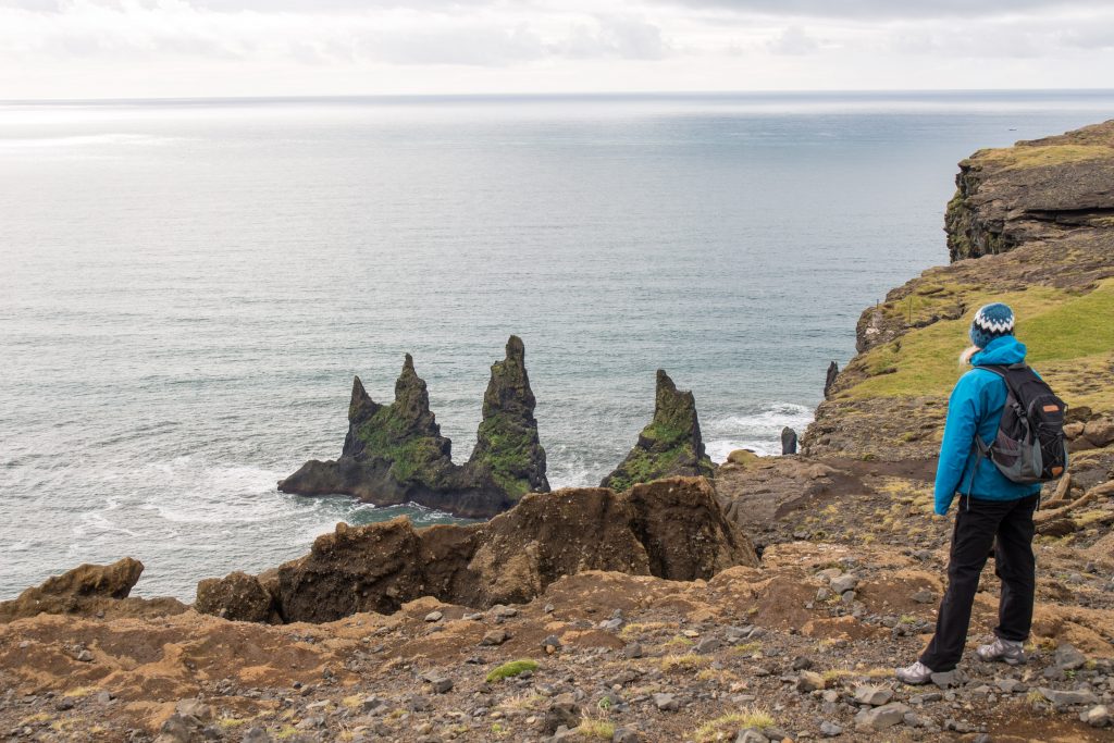 Wilde Küstenlandschaft mit Felsen im Meer, Reisende schaut auf das Meer
