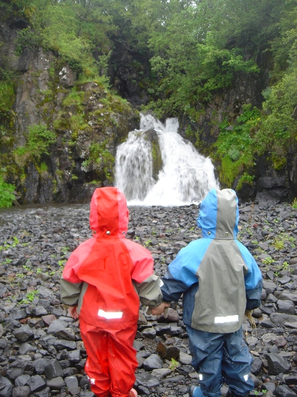 Kinder in Island bestaunen einen Wasserfall