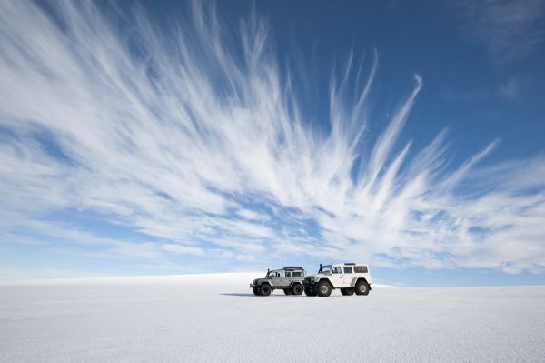 Zwei Jeeps in einer leeren, weißen Wüste in Island