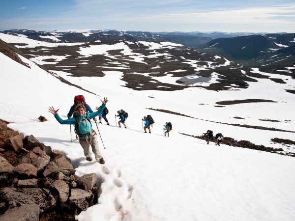 Wandergruppe läuft über ein Schneefeld in Island